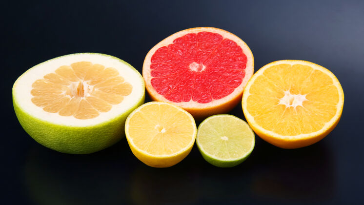 五颜六色在深色的背景上切块不同的柑橘类水果食物圆形切的