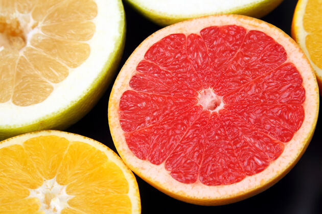 黄色在深色的背景上切块不同的柑橘类水果橘子葡萄柚切的
