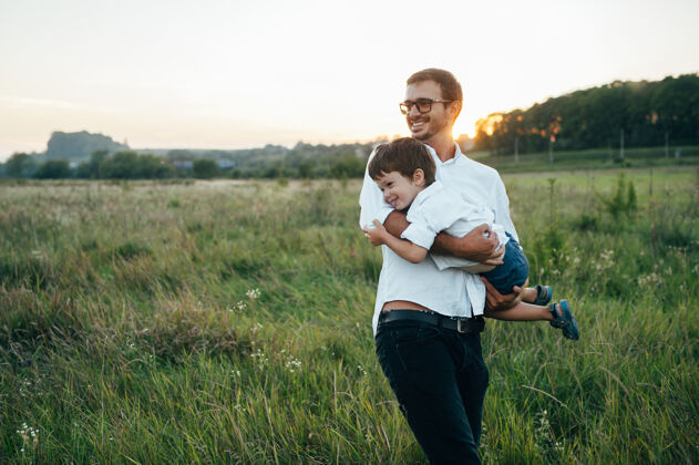 在一起英俊的爸爸带着他可爱的小儿子在绿草如茵的草地上玩耍孩子风景休息
