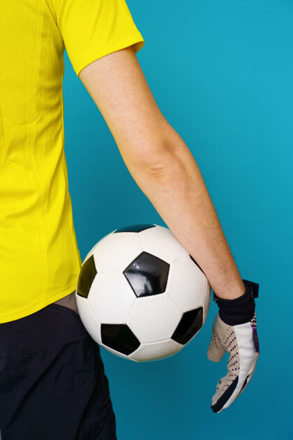 欢呼男球迷穿黄色t恤 蓝色背景上有足球训练球球员