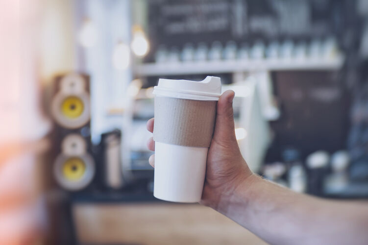 咖啡在咖啡馆的酒吧背景下 一个男人手里拿着一个装咖啡的硬纸板玻璃杯的模型纸板人摩卡咖啡