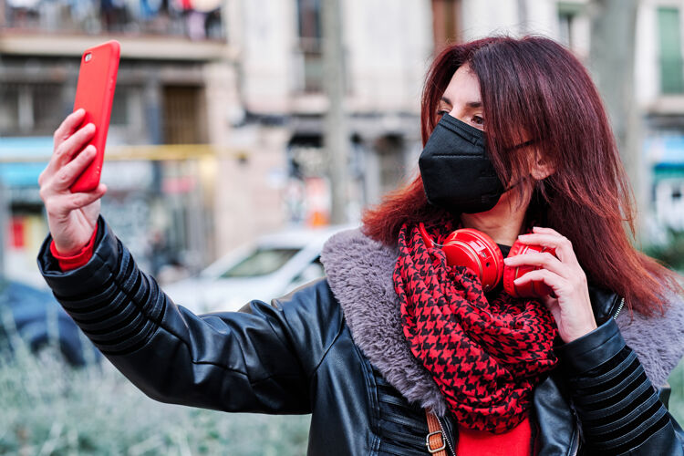 社会距离一名妇女戴着口罩 站着用手机自拍户外.新正常寿命城市概念概念聊天户外人