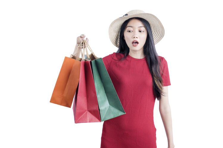 时尚一个戴着帽子的亚洲女人 手上拎着购物袋 隔着白墙女人购物者购买