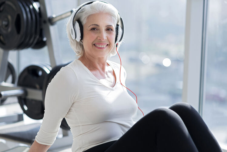 能量令人愉快的放松快乐满意的资深女士 戴着耳机听音乐 在健身房锻炼后放松健身房活跃满意
