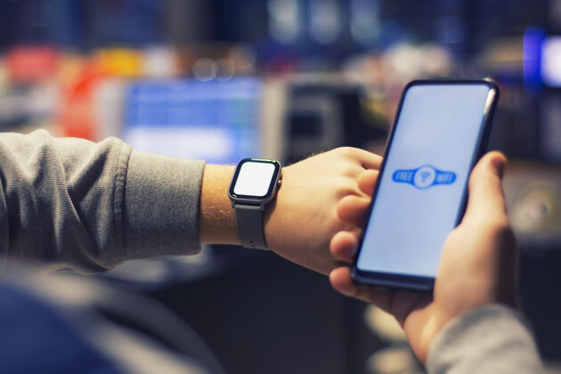 呼叫男人手上拿着一部带有近距离wi-fi图标的智能手机和一块智能手表技术屏幕智能手表