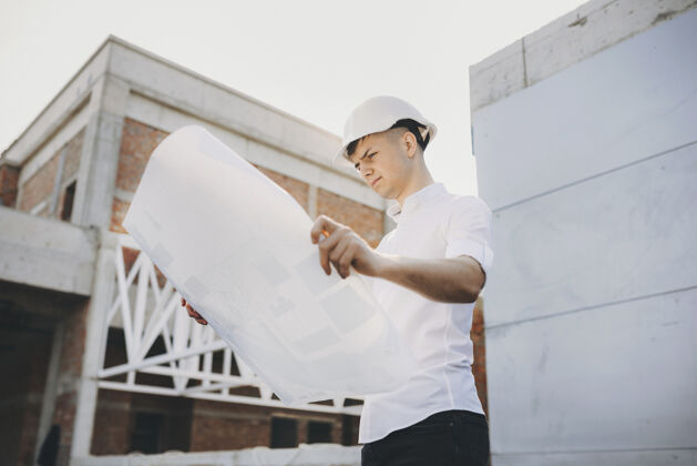 商业一位男建筑师的画像 他正在看一栋正在施工的建筑早上就在这座建筑上工人项目地产