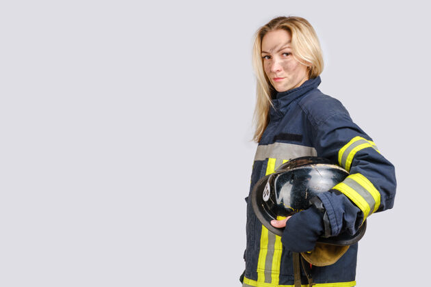 强壮穿着消防员制服的脏脸女人手里拿着安全帽紧急保护肮脏的脸
