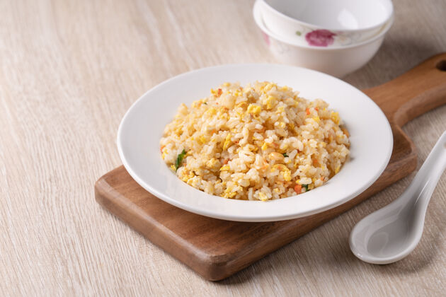 食物在明亮的木桌上用白色盘子里的樱花虾做的中国炒饭的特写镜头菜肴米饭薯条