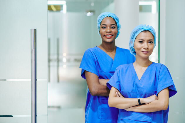 女性微笑着站在医院走廊里的多民族护士 戴着一次性帽子 戴着磨砂棒擦伤矫正医生