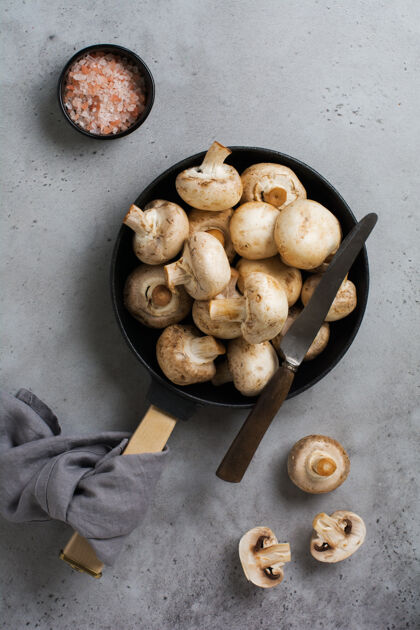 营养生蘑菇放在一个旧的水泥灰色乡村餐桌上 放在一个铸铁的老平底锅里油炸上衣查看香肠菜单素食