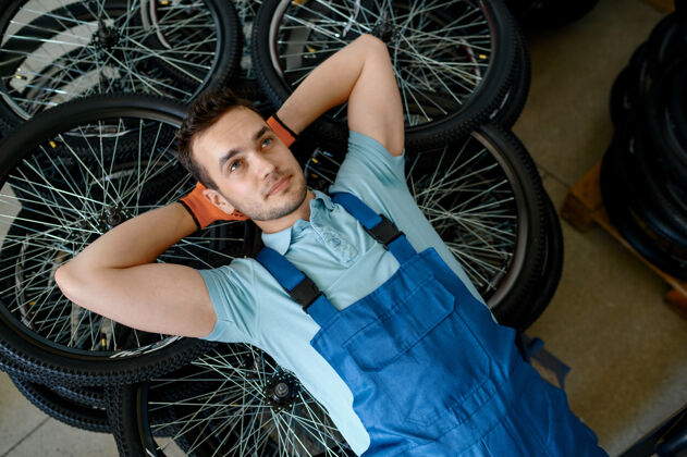 铝躺在一堆自行车轮子上的男工人工厂自行车轮圈车间流水线 轮圈零件安装 现代工艺特写人辐条