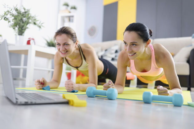 重两个女人在家里参加体育活动 并站在一旁plank.online公司检疫期间的运动理念私人教练体育强壮
