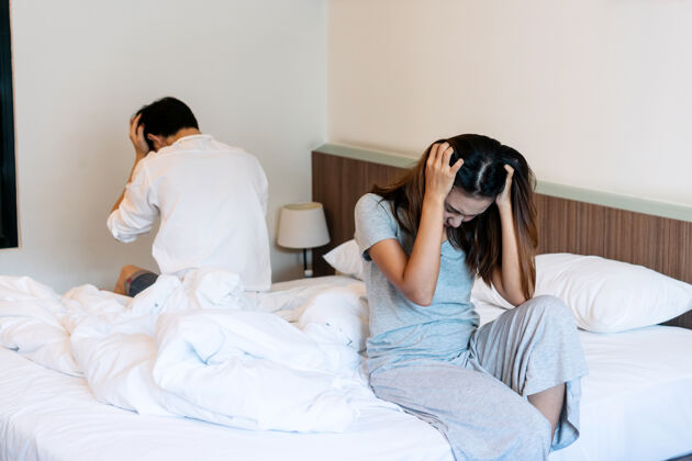 不安吵架的年轻夫妇坐在家里的床上爱关系背部