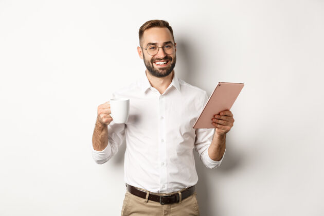 Man满意的老板喝茶和使用数字平板电脑 阅读或工作 站在白色背景下BrokerCoffeepicture