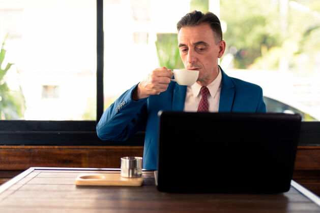 男性成熟英俊的意大利商人在咖啡店放松的画像城市笔记本电脑成熟