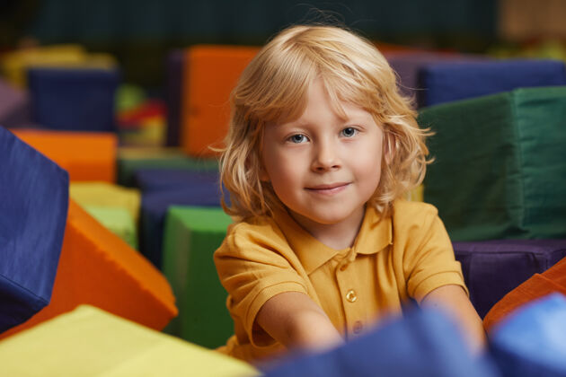 快乐可爱的金发小男孩在公园里玩大色块的时候看着前面享受坐着学习