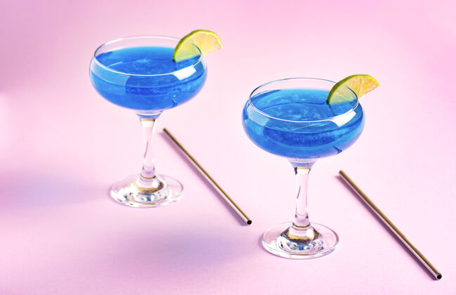 酒精鸡尾酒闪闪发光的蓝色闪光饮料鸡尾酒杯装饰着石灰站在一个粉红色的闪亮蓝色闪光蓝色泻湖