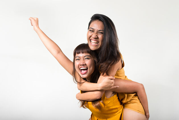 骑马两个年轻的亚洲女人一起对抗白色空间拥抱女同性恋友谊