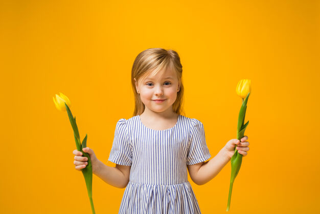花一个快乐的金发女孩拿着两朵黄色的郁金香单身给予欢呼
