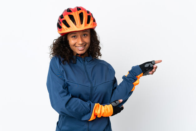 深色十几岁的骑自行车的女人被隔离在白色背景下 手指指向侧面人骑年轻