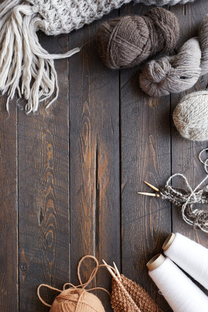 工艺产品木制桌子的高角度视图 上面有毛线球和成品羊毛衣服缝纫针旧的材料