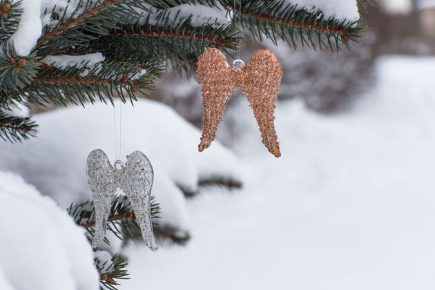霜冻两个天使的翅膀挂在云杉树枝上圣诞节木头自然