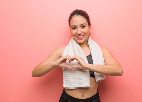 运动年轻的健身女用手做心形爱乐趣运动装