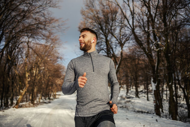 运动员运动员在雪地小道上的森林里慢跑冬天健活方式 冬季健身雪天气微笑