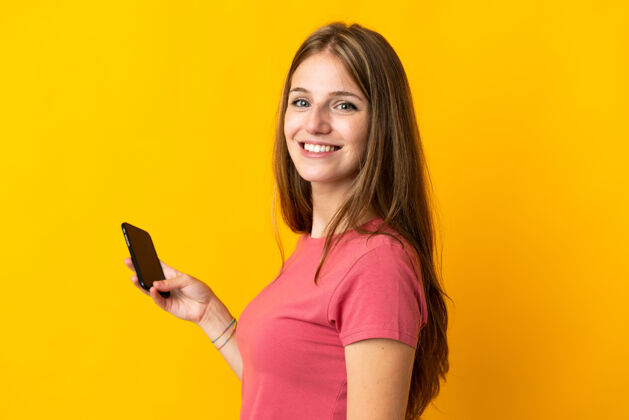 乐趣年轻女子用手机孤立的黄色笑了很多手机通话肖像