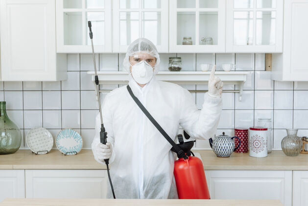 房屋一个男人在厨房里穿着防护服用消毒喷雾剂消毒家居用品和家具大流行的概念消毒冠状病毒或冠状病毒专业人员清洁剂预防