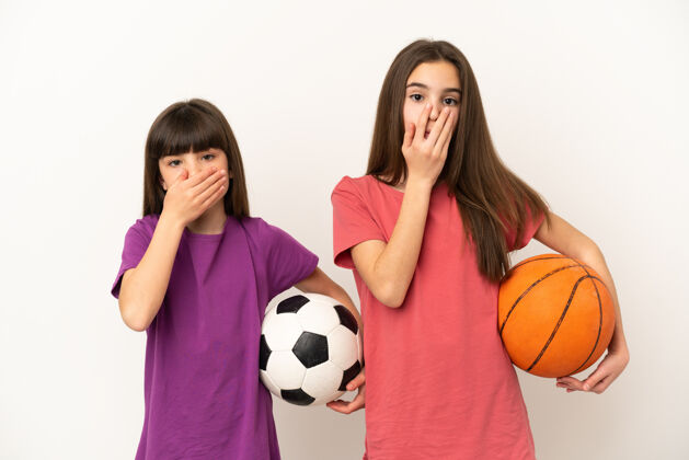惊喜踢足球和打篮球的小姐妹们被隔离在白色的背景上 用手捂住嘴说不恰当的话表情年轻爱好