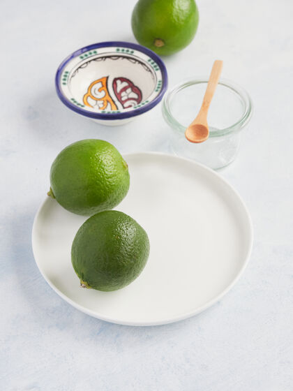 配料在一个白色盘子里放一对完整的酸橙 可以在饮料或食物中使用柑橘健康柑橘