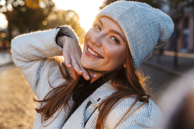 微笑一位穿着秋衣戴秋帽的美丽年轻女子在户外散步 自拍街道风格年轻