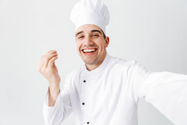 人类穿着制服的快乐厨师长孤立地站在白墙上 自拍自信风格就业