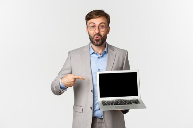 胡须笑容可掬的帅哥商人和眼镜的肖像 手指指着笔记本电脑屏幕帅气表演时尚