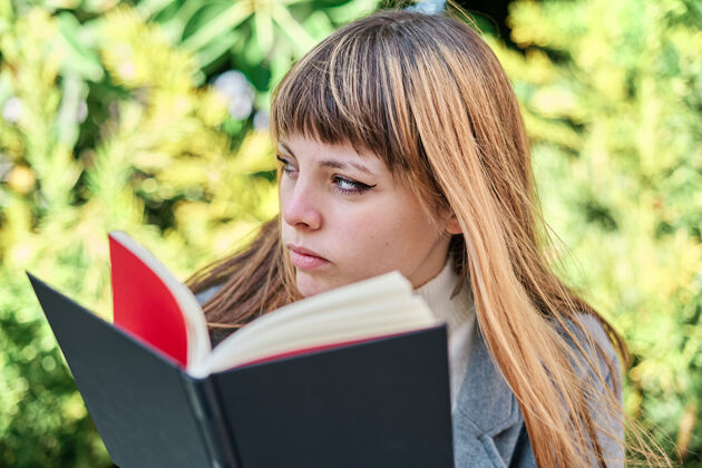 花园一张蓝眼睛的白人金发年轻女子在公园看书的特写照成人书女性
