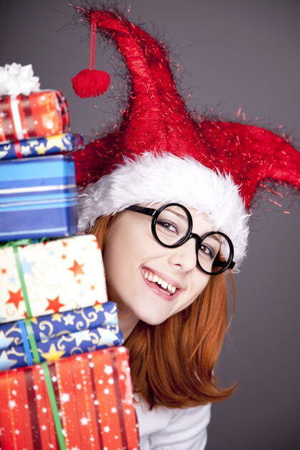 礼物滑稽的红发女孩戴着圣诞帽 手里拿着礼品盒圣诞老人节日女性