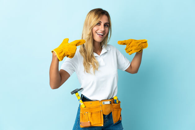 工艺年轻的金发乌拉圭电工蓝女士竖起大拇指女性金发木匠