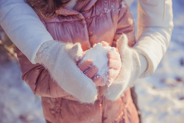 季节冬天 雪地里 妈妈在街上用皮手套牵着女儿的手户外成人父母