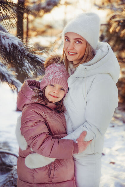 成人妈妈和女儿在冬季公园玩得很开心雪童年快乐