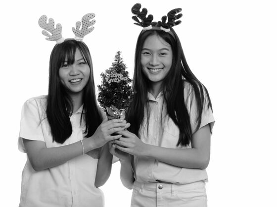 肖像两个年轻漂亮的亚洲少女一起被隔离在黑白相间的白墙上女孩女性亚洲