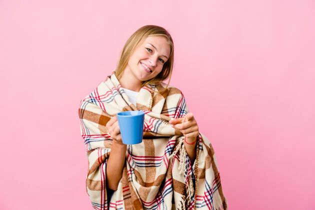 咖啡年轻的俄罗斯女子裹着毯子喝着咖啡欢快地笑着指着前面温暖沙发房子