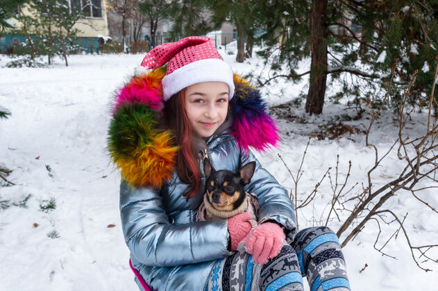 衣服美丽的女孩带着吉娃娃上了大自然一个十几岁的女孩抱着一只狗吉娃娃雪地过冬自然女性狗
