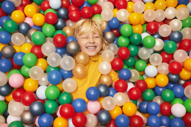 童年快乐的小男孩躺在游泳池里 手里拿着彩球 享受着游戏孩子笑特写