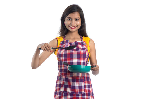 完成一个年轻的印度女人拿着一个白色的厨房用具看面部餐具