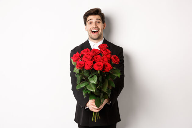 新郎身着黑色西装的帅哥男友的肖像 手持一束红玫瑰 面带微笑魅力结婚珠宝