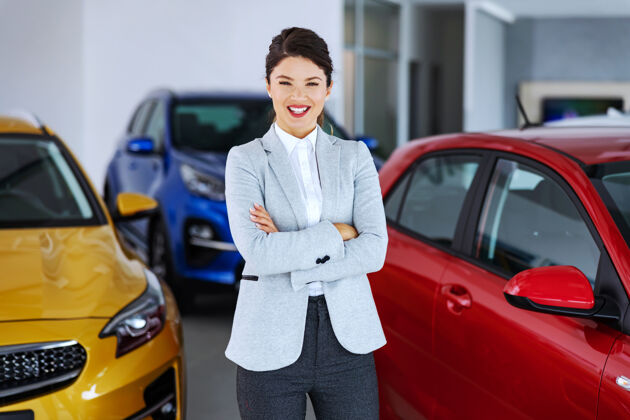 经销商友好微笑的汽车销售商站在汽车沙龙双臂交叉 等待客户来销售交叉微笑合同