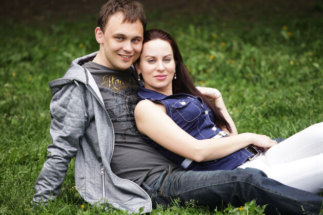 快乐美丽的年轻夫妇坐在公园里放松的画像夏天坐着休闲