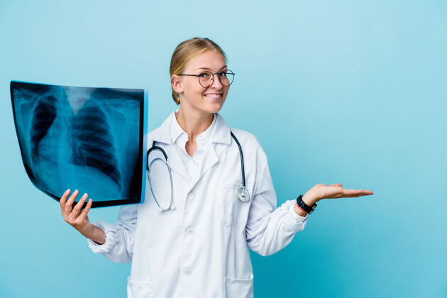 惊人年轻的俄罗斯女医生拿着蓝色的骨头扫描仪 手掌上拿着复印件放射患者临床