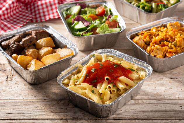 海鲜饭把健康食品放在木桌上的锡箔盒里带走小吃蔬菜晚餐